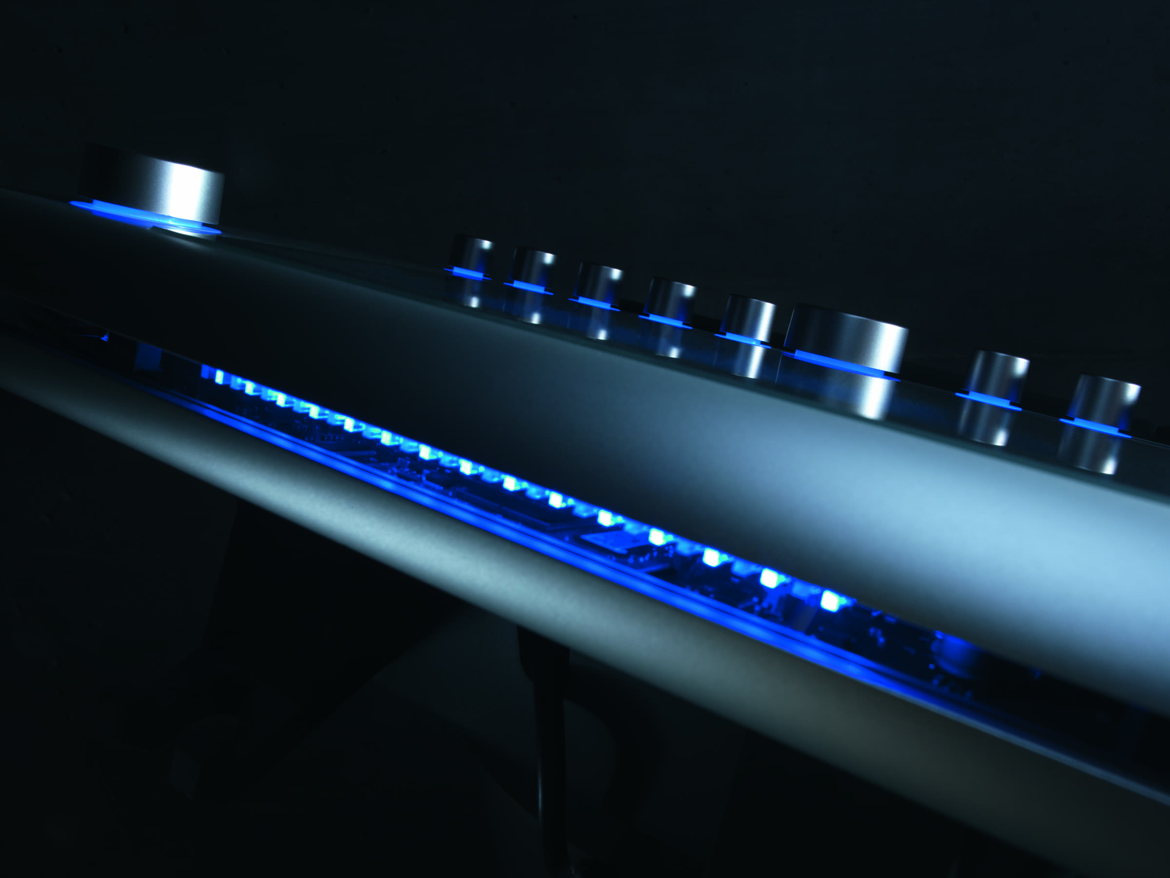 Detalhe macro de uma consola MIHA BODYTEC iluminada por LEDs azuis — tecnologia de eletroestimulação muscular fabricada na Alemanha.